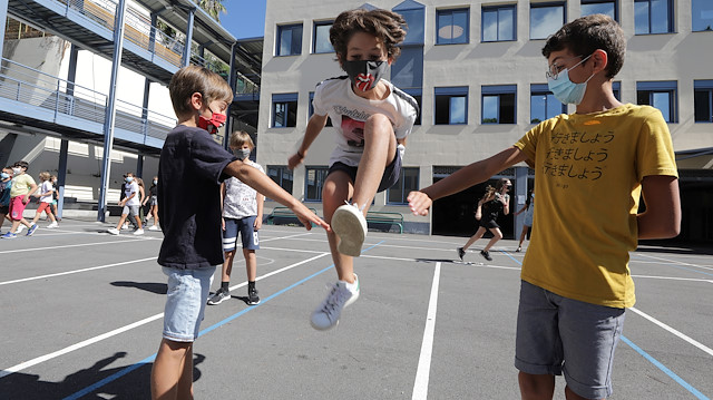 Secondary school students, wearing protective face masks, play in the courtyard
