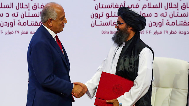 Mullah Abdul Ghani Baradar, the leader of the Taliban delegation, and Zalmay Khalilzad