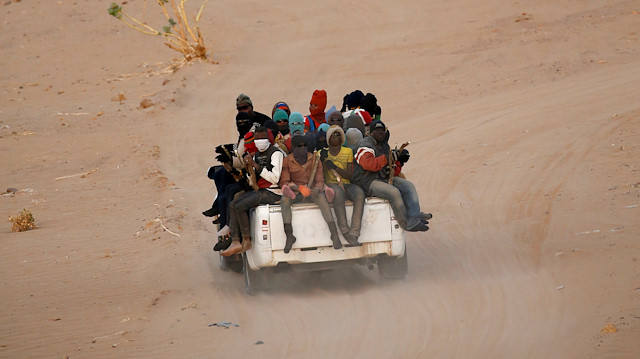 FILE PHOTO: Migrants crossing the Sahara desert into Libya ride on the back of a pickup truck outside Agadez, Niger, May 9, 2016. 