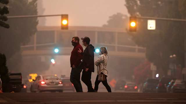 Local residents cross a street as smoke from wildfires covers an area near Salem, Oregon, U.S., September 10, 2020