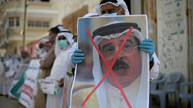 A Palestinian man holds a crossed out poster depicting Bahrain's King Hamad bin Isa Al Khalifa during a protest against Bahrain's move to normalize relations with Israel, in the central Gaza Strip 