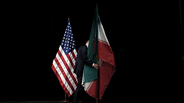  A staff member removes the Iranian flag from the stage after a group picture