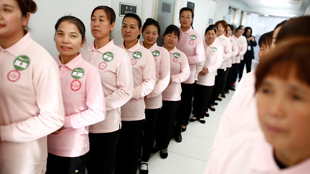 Graduates of Ayi University, a training program for domestic helpers, line up to meet potential employers in Beijing, China December 11, 2018. The training program teaches childcare, early education, housekeeping and other skills for domestic workers and is designed to meet the demand of China's middle class after the country scrapped the one-child policy. Picture taken December 11, 2018. REUTERS/Thomas Peter

