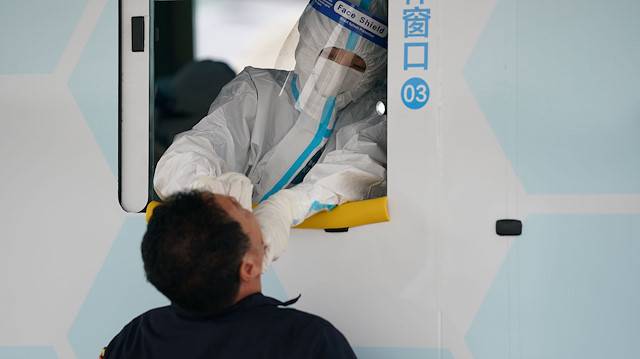 A medical worker in protective suit collects, through a window of a vehicle, a swab from a man for nucleic acid testing following the new outbreak of the coronavirus disease (COVID-19) in Beijing, China June 28, 2020. cnsphoto via Reuters