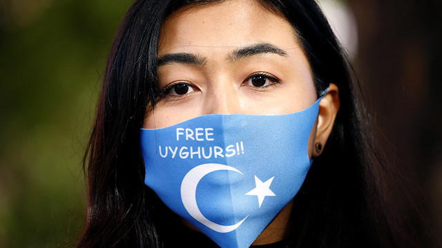 A woman wearing a mask with a Uyghur flag takes part in a rally during China's Foreign Minister Wang Yi's visit in Berlin, Germany September 1, 2020. REUTERS/Michele Tantussi

