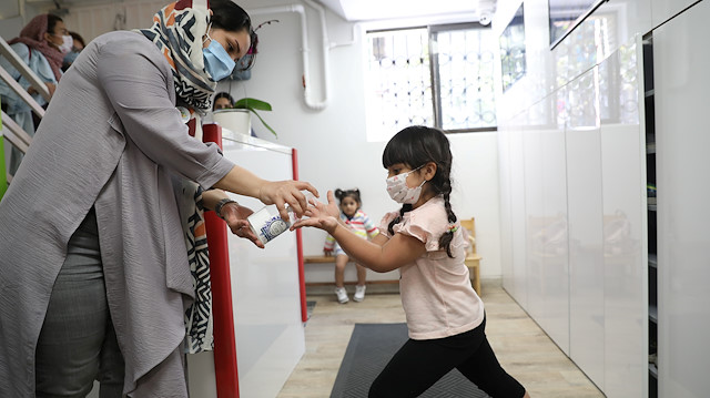 A girl wears a protective face mask gets her hands sanitized by her caretaker at Ghesseye Man (My Story) kindergarten, amid the outbreak of the coronavirus disease (COVID-19), in Tehran, Iran September 27, 2020. Picture taken September 27, 2020. Majid Asgaripour/WANA (West Asia News Agency) via REUTERS 