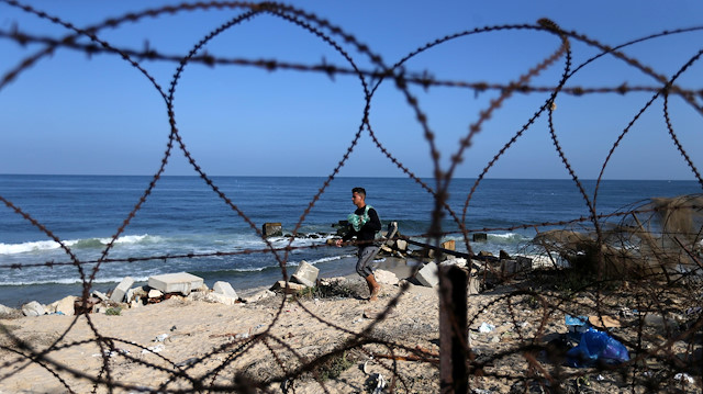 A fisherman is seen through a fence as he walks near the maritime border between Gaza and Egypt, a day after the dead bodies of two Palestinian fishermen were returned from Egypt to Gaza, in the southern Gaza Strip September 27, 2020.