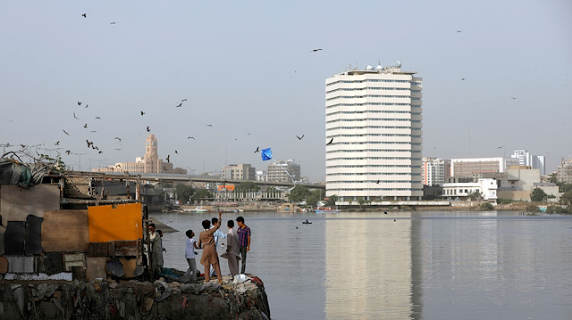 Boys gather outside a makeshift house as they fly a kite with the Pakistan National Shipping Corporation (PNSC) building in the background, amid the coronavirus disease (COVID-19) pandemic, in Karachi, Pakistan October 12, 2020.