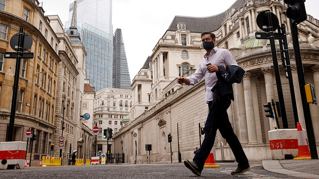 FILE PHOTO: A man wearing a face mask crosses the road in the City of London financial district amid the outbreak of the coronavirus disease (COVID-19), in London, Britain September 23, 2020. 