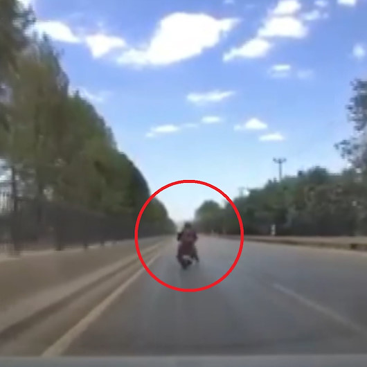 Motosikletlinin seyir halindeyken yerdeki çöpü ayağıyla alma anı kamerada