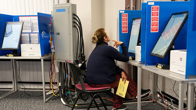 A poll worker begins packing up supplies at a polling cente