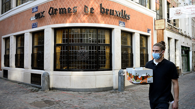 A man wearing a protective face mask walks past a restaurant, forced to close for four weeks, after a Belgian federal government decision in order to tackle a surging second wave of the coronavirus disease (COVID-19) in the country, in Brussels, Belgium October 19, 2020.