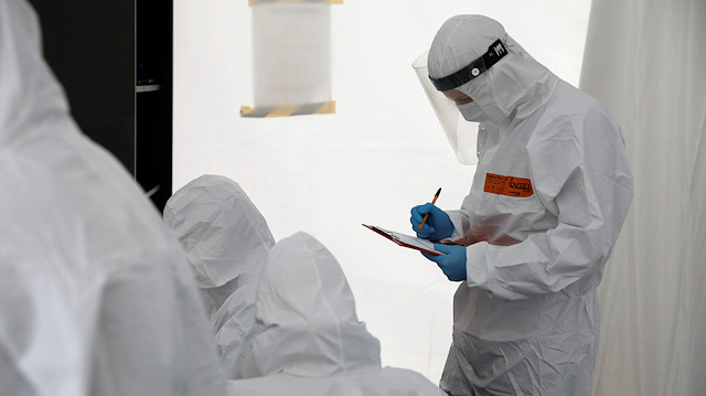 FILE PHOTO: A man wearing a protective coverall fills up the form before performing tests for the coronavirus disease (COVID-19) at a drive-thru testing centre in Warsaw, Poland, October 2, 2020. 