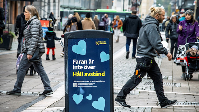 People walk near a trash can with a sign reading "The danger is not over - Keep your distance" on a pedestrian street as the coronavirus disease (COVID-19) outbreak continues in Uppsala, Sweden October 21, 2020