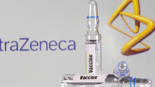 A test tube labeled with the vaccine is seen in front of AstraZeneca logo