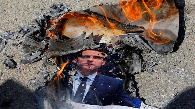 A picture of French President Emmanuel Macron is burnt by Palestinians during a protest against the publications of a cartoon of Prophet Mohammad in France and Macron's comments, near Hebron in the Israeli-occupied West Bank October 27, 2020. REUTERS/Mussa Qawasma TPX IMAGES OF THE DAY

