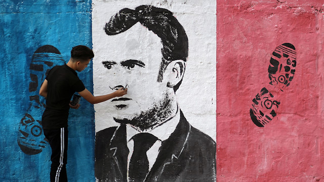 A Palestinian artist paints an anti-French President Emmanuel Macron mural 