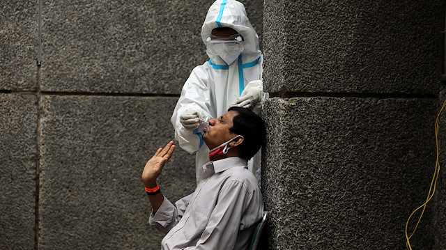 A healthcare worker wearing personal protective equipment (PPE) collects a swab sample from a man amidst the spread of the coronavirus disease (COVID-19), at a testing center in New Delhi, India October 29, 2020. REUTERS/Anushree Fadnavis

