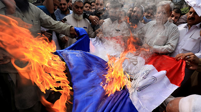 People chant slogans as they set fire to a France's flag during a protest against the cartoon publications of Prophet Mohammad in France and comments by the French President Emmanuel Macron, in Peshawar, Pakistan October 28, 2020. REUTERS/Fayaz Aziz TPX IMAGES OF THE DAY  