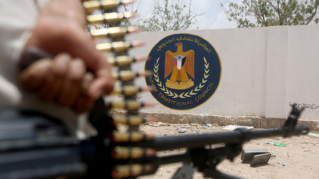 FILE PHOTO: A Yemeni government soldier holds a weapon as he stands by an emblem of the STC at the headquarters of the separatist Southern Transitional Council in Ataq, Yemen August 27, 2019. 