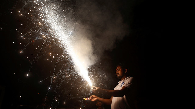 A man holds a firecracker as it burns during Diwali, the Hindu festival of lights