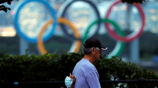 The giant Olympic rings are seen as a passerby walks holding a protective face mask two days before the start of the one-year countdown to the Tokyo Olympics that have been postponed to 2021 due to the coronavirus disease (COVID-19) outbreak, at the waterfront area at Odaiba Marine Park in Tokyo, Japan July 21, 2020