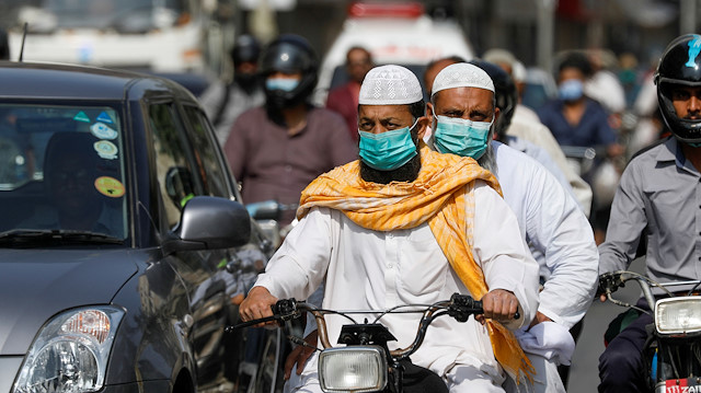 Men wear protective masks as they ride a motorcycle 