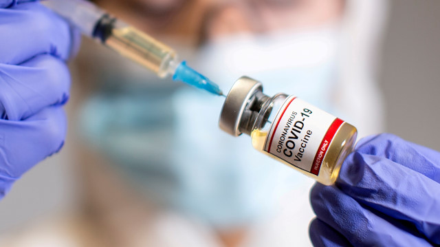 FILE PHOTO: A woman holds a small bottle labeled with a "Coronavirus COVID-19 Vaccine" sticker and a medical syringe in this illustration taken October 30, 2020. REUTERS/Dado Ruvic/File Photo


