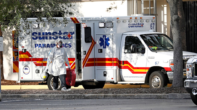 A paramedic dressed in personal protective equipment exits an ambulance