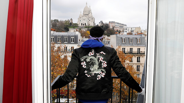 Asylum-seeker Ibrahim looks at the Sacre Coeur Cathedral from his room at the Hotel Avenir 