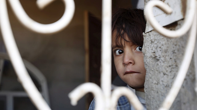 A boy looks from the window of his family's house, damaged by a Saudi-led air strike, on the outskirts of Yemen's capital Sanaa December 29, 2015.