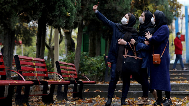 Women wearing protective face masks take a selfie in a park in Tehran 