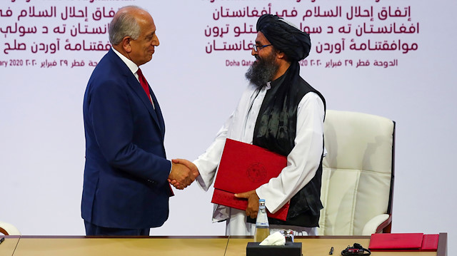 Mullah Abdul Ghani Baradar, the leader of the Taliban delegation, and Zalmay Khalilzad