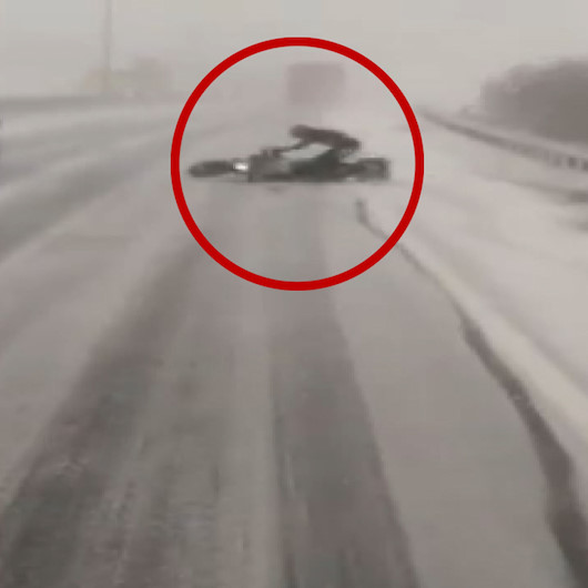 Karlı yolda devrilen motosikletli otomobilin altında kalmaktan son anda kurtuldu