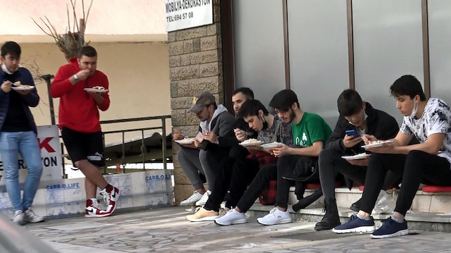 Sokakta yemek yiyen gençler.
