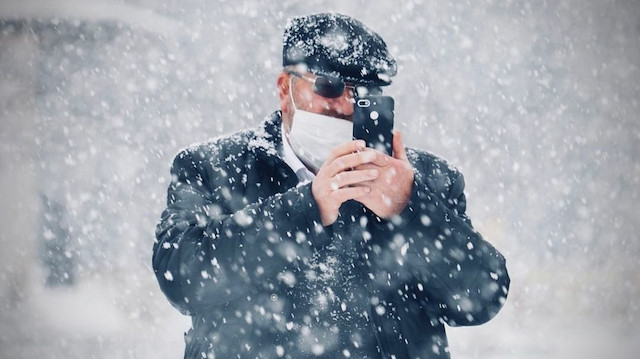 Erzurum'da kar yağarken fotoğraf çeken bir vatandaş.