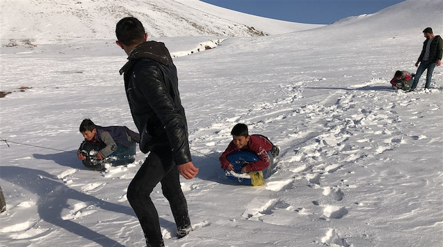 Karda bata çıka dağa tırmanmayı başaran gençler, yüzüstü uzandıkları bidonlarla kaymaya başlıyor.