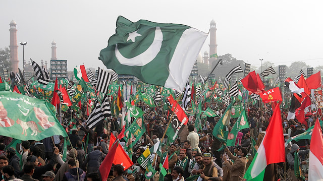 Supporters of the Pakistan Democratic Movement (PDM), an alliance of political opposition parties, wave flags as they listen to the speeches of their leaders during an anti-government protest rally, in Lahore, Pakistan December 13, 2020.