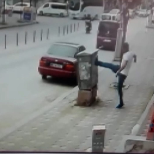 Önce aydınlatma direğini ardından telefon panosunu tekmeledi