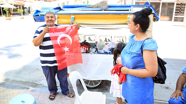 Çöpte bulduğu bayrakları temizleyip 15 Temmuz için esnafa dağıttı