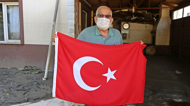 Evde mahsur kalan vatandaş helikopterin görmesi için çatıdan Türk bayrağı salladı.