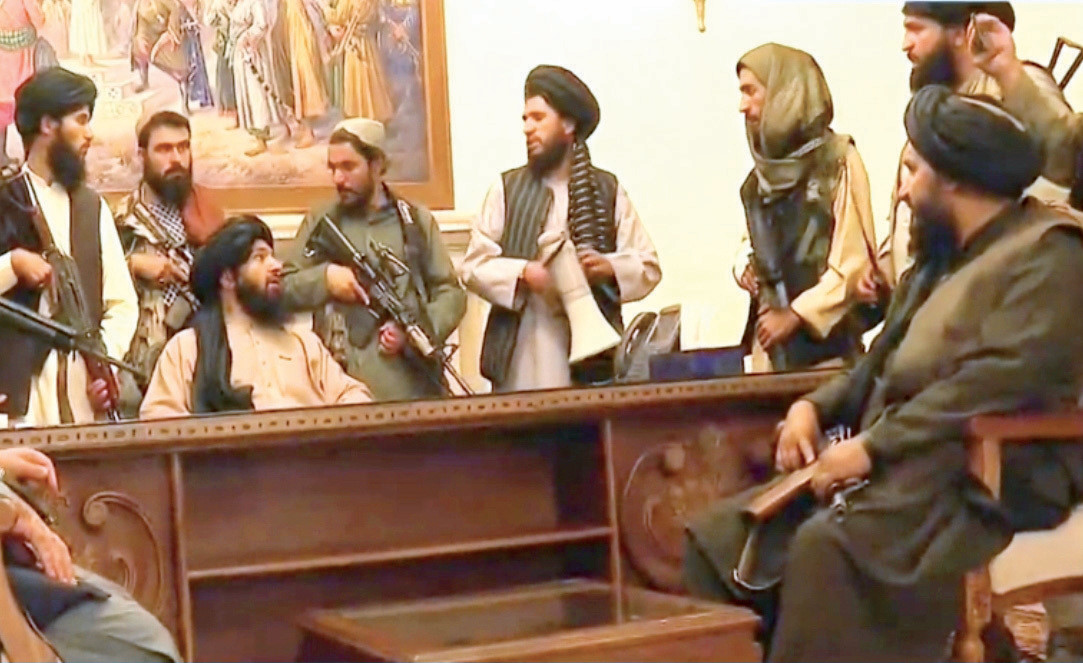 Taliban güçleri Başkanlık sarayını ele geçirdikten sonra Devlet Başkanı Gani’nin makamında poz verdi.