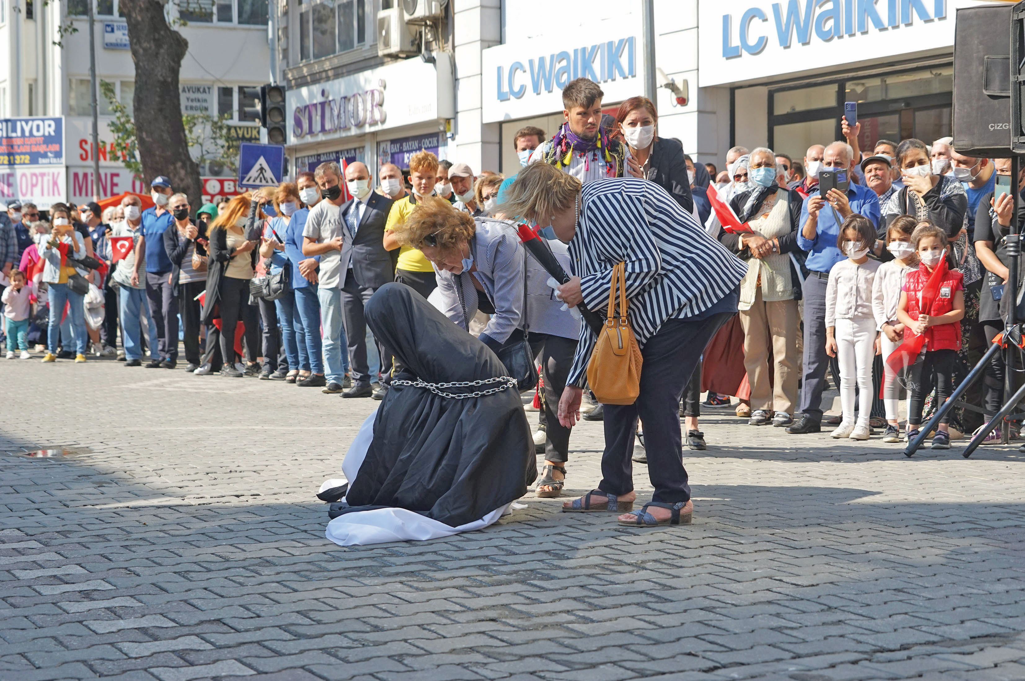 Törende zincire vurulan çarşaflı bir kadına diz çöktürüldü.