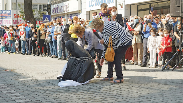 Törende zincire vurulan çarşaflı bir kadına diz çöktürüldü.