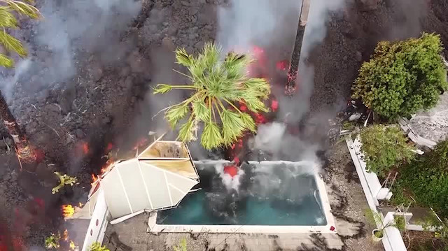 Drone ile çekilen görüntüde lavlar, ulaştığı bir evin havuzunu doldururken, bahçedeki ağacı da tutuşturdu.