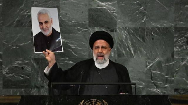 İran Cumhurbaşkanı Reisi, BM kürsüsünde Süleymani'nin fotoğrafını gösteriyor.
