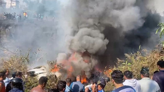 Kurtarma ekipleri ile bir grup insanın, uçağın enkazının etrafında toplandığı ve olay yerinden dumanın yükseldiği görüldü.