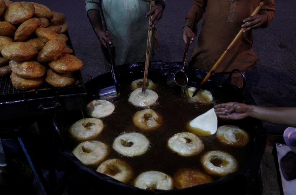 Men prepare "khajla", a traditional delicacy consumed during the month of Ramadan, while selling them from a stall along a road ahead of Muslim holy month of Ramadan in Karachi, Pakistan, May 25, 2017.