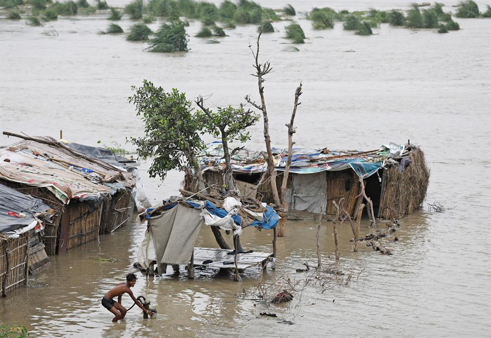 A man collects drinking water from a hand pump next to his shanty
