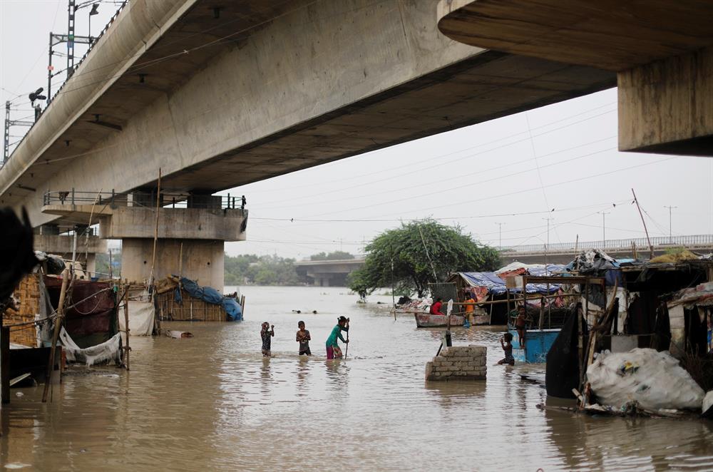 Children wade through a flooded street at a slum area